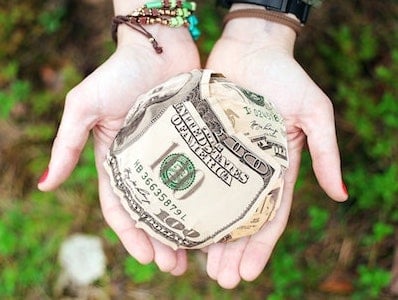 A person holding a dollar bill in their hands.