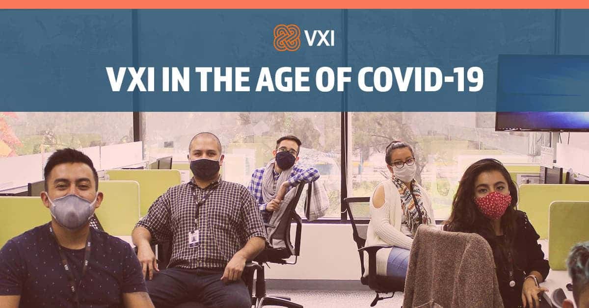 Photo of VXI agents seated at their desks, facing the camera, all wearing COVID-19 masks for safety.