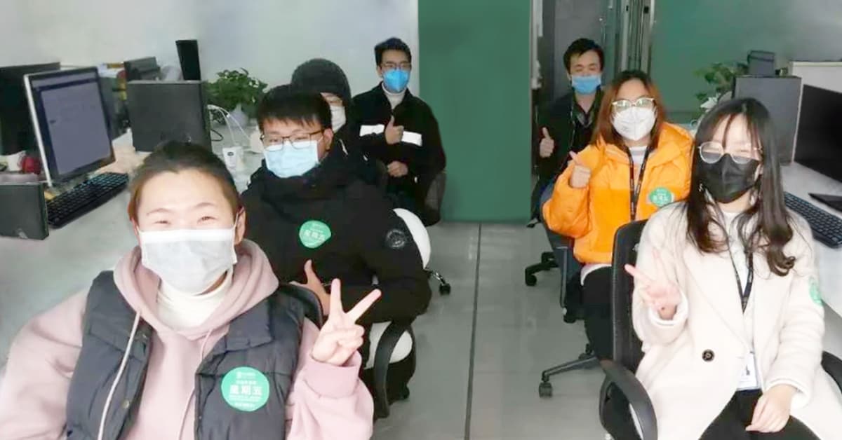 Photo of a team of VXI call center employees wearing protective face masks while working together during the 2019 pandemic.