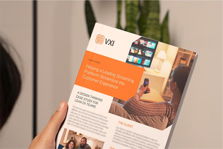 A person reading a VXI case study brochure on 'Helping a Leading Streaming Platform Streamline the Customer Experience', showing someone using a smartphone.